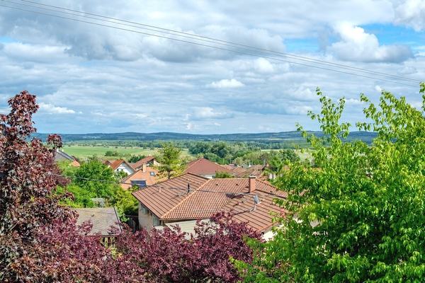 Panorámás kilátás a dombos, zöld tájra és a lakópark cseréptetős házaira